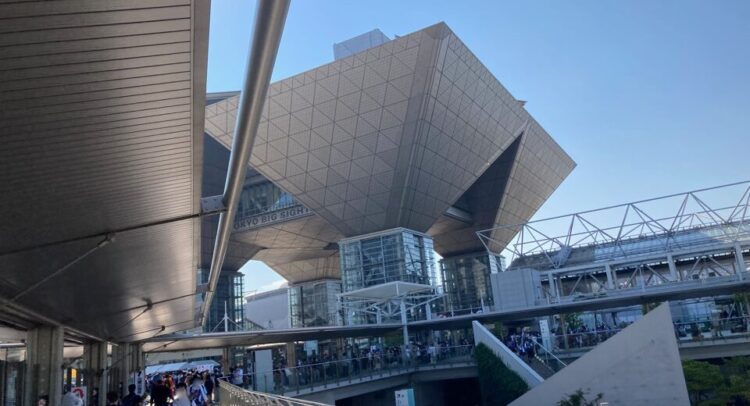 この写真は東京ビッグサイト（Tokyo Big Sight）を撮影したものです。東京ビッグサイトは、日本国内で最大級の国際展示場であり、様々な大規模イベントやコンベンションが開催される場所として知られています。特徴的な逆ピラミッド型の屋根が印象的で、イベント会場として広く利用されています。