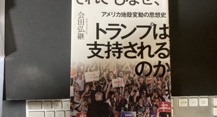 黒い背景に置かれた本の表紙。「それでもなぜ、トランプは支持されるのか」というタイトルが大きく書かれており、副題として「アメリカ地殻変動の思想史」が記載されています。著者は会田弘継。本の下半分には「SAVE AMERICA!」と書かれたプラカードを掲げる群衆の写真が掲載されています。本の周囲には白いキーボードと黒いデスクが映り込んでいます。