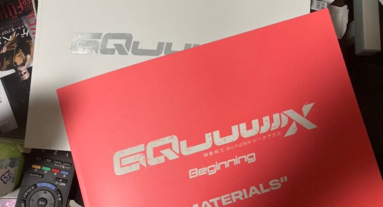 画像には『機動戦士Gundam GQuuuuuuX』の「Beginning MATERIALS」と書かれた赤い冊子と白いボックスが映っています。タイトルのデザインはスタイリッシュで、未来感のあるフォントが印象的です。